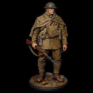 Puede incluir: Figura detallada de un soldado de la Primera Guerra Mundial con uniforme marrón, casco y capa, sosteniendo un rifle. La figura tiene una máscara de gas, una mochila y botas marrones. El soldado está sobre una base circular.