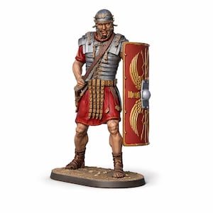 Può includere: Statuetta dettagliata di un legionario romano, vestito con armatura argentata, tunica rossa e gonna abbinata. Il legionario tiene uno scudo rosso con disegni di ali dorate. La figura è su una base marrone.