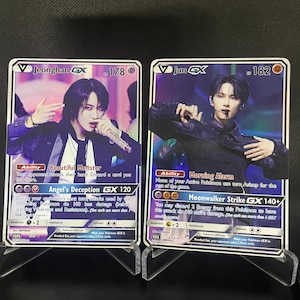 以下が含まれることがあります： 韓国のポップスターのグループが描かれたポケモンカードゲームのカード2枚。カードはホログラフィックで、JeonghanとJunのキャラクターが描かれている。カードには「Jeonghan GX」と「Jun GX」の文字が書かれている。