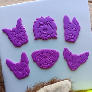 May include: Six purple silicone dog breed cookie cutters, including a pug, a chihuahua, a french bulldog, a yorkie, a german shepherd, and a doodle.