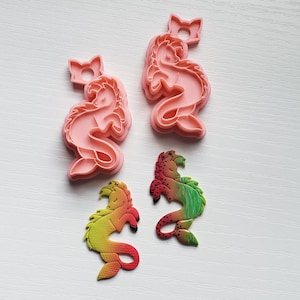 May include: Two pink silicone molds of a seahorse with a crown on its head. Two seahorse charms are also shown, one is green and yellow, the other is red and green.