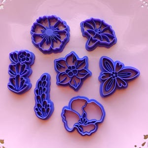 May include: Set of seven purple plastic cookie cutters shaped like flowers and leaves.