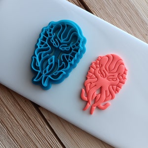 May include: Two cookie cutters, one blue and one orange, shaped like a creature with tentacles.