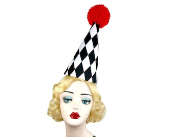 May include: A black and white checkered party hat with a red pom-pom on top. The hat is worn by a mannequin with blonde hair.