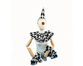 May include: A black and white checkered clown costume with a pointed hat, a ruffled collar, and matching wrist cuffs. The costume is displayed on a mannequin with a red clown nose.