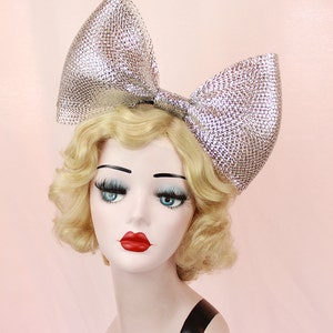 May include: A large silver sparkly bow headband. The bow is made of a mesh material and is very large, covering most of the head.