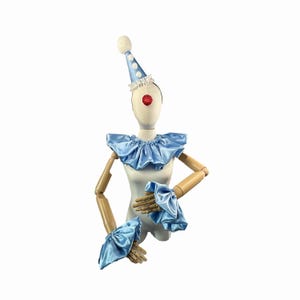 May include: A clown costume set featuring a light blue satin ruffled collar, wrist cuffs, and a matching cone hat with white polka dots and a fluffy pom-pom. A red nose completes the look.