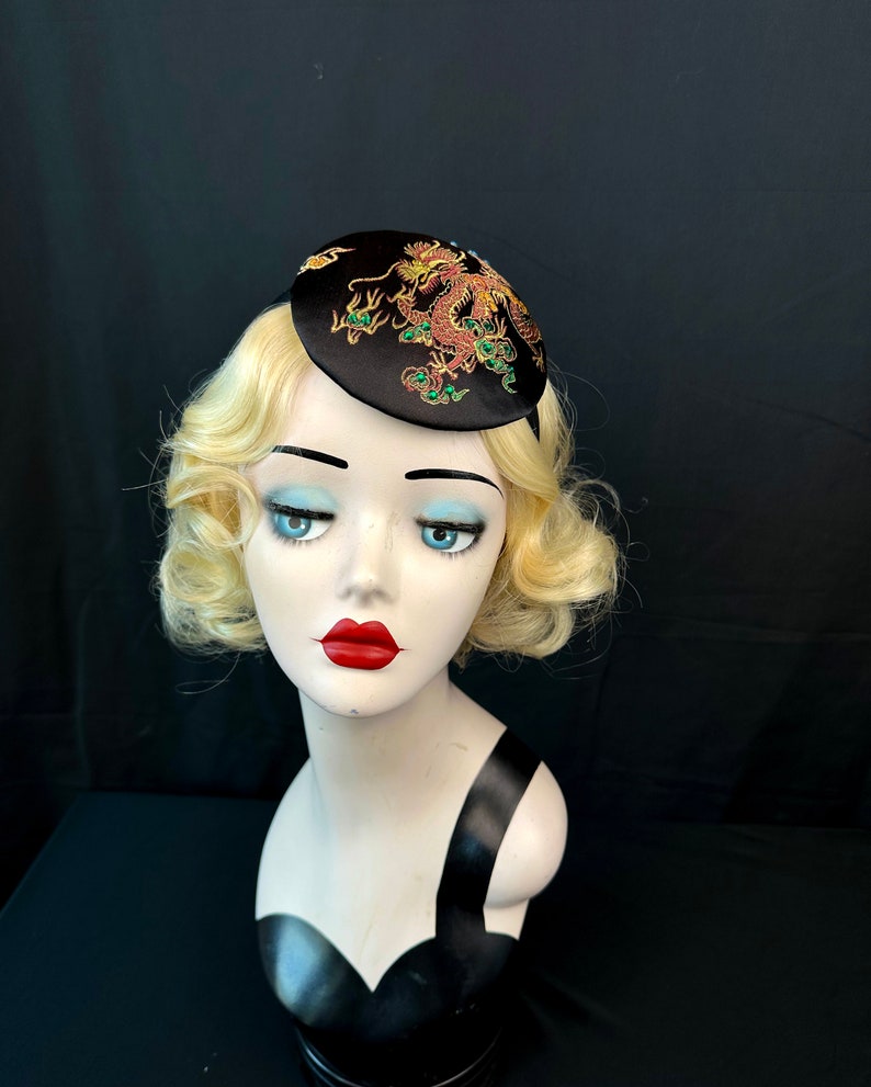 May include: A black satin hat with a gold and green embroidered dragon design.