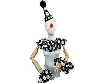 Puede incluir: Un disfraz de payaso de lunares negros y blancos con un sombrero y puños a juego. El disfraz está en un maniquí con una nariz de payaso roja.
