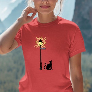 May include: Red t-shirt with a black cat silhouette and a streetlight graphic with a yellow light. The streetlight has a sign that reads "London Town".
