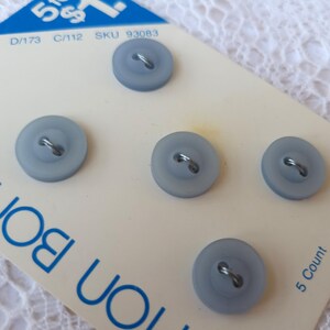 May include: Five light blue buttons on a white card. The buttons are round with two holes and a metal loop on the back. The card has blue text and the text "5 Count".