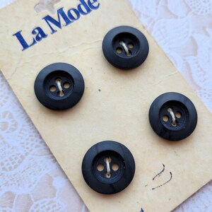 May include: Four black plastic buttons with four holes each, packaged on a card with the text "La Mode" printed on it.