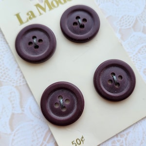 May include: A card with four dark brown buttons with four holes each. The card has the text "La Mode" and "50¢" printed on it.