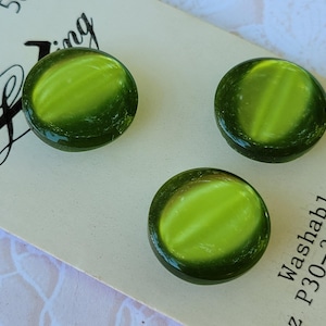 May include: Three round, olive green buttons with a lighter lime green center stripe, mounted on a white display card. The card features the text "Sewing" and "Washable P30-3/4". Each button has a smooth, glossy, domed surface finish.