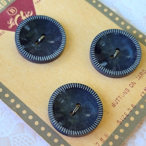 May include: Three round, dark navy blue buttons with a textured, ribbed edge and a central two-hole design, attached to a tan cardboard display card featuring the Le Chic brand logo and the text Buttons on Card and Size 36.