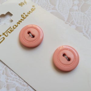 May include: Two coral-colored buttons with a decorative edge and metal shank are displayed on a cream-colored card. The card has the word "Streamline" in gold script. The buttons are new and unused.
