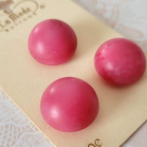 May include: Three round, dome-shaped buttons in a vibrant pink marbled finish, attached to a cream-colored display card. The card features the text La Mode Buttons at the top and the number 78149 printed on the lower right side of the card.