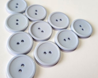 May include: Ten light blue plastic buttons with two holes each. The buttons are arranged in a triangular shape.