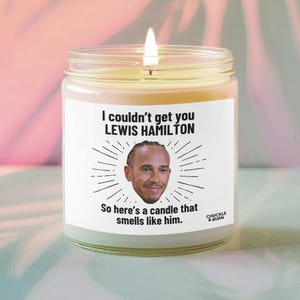 May include: A lit scented candle in a glass jar. The label features the text "I couldn't get you LEWIS HAMILTON" with a photo of Lewis Hamilton. The text continues, "So here's a candle that smells like him."