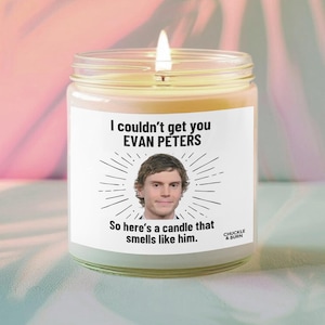 Może przedstawiać: Zapalone świeca w szklanym słoiku z białą etykietą. Etykieta zawiera tekst "I couldn't get you EVAN PETERS" nad zdjęciem mężczyzny i "So here's a candle that smells like him."