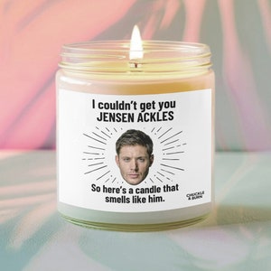 May include: A white candle with a black label that reads "I couldn't get you JENSEN ACKLES So here's a candle that smells like him."  The label also includes a black and white illustration of a man's face and the words "CHUCKLE & BURN".