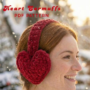 May include: Red heart-shaped earmuffs, a cozy winter accessory, are featured in this image. The earmuffs are made of a soft, textured material and are worn by a person. The text "Heart Earmuffs PDF Pattern" is visible in the image.