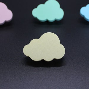 Può includere: Quattro forme di nuvole in feltro di colore pastello. Le nuvole sono rosa, azzurro, verde chiaro e giallo. Le nuvole sono disposte a semicerchio su uno sfondo nero.