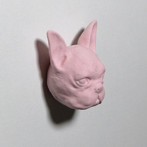 Könnte beinhalten: Eine rosafarbene Keramikfigur eines französischen Bulldoggenkopfes.