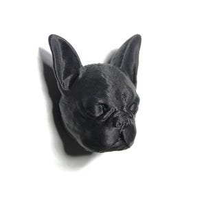 Puede incluir: Una figurita de cabeza de Bulldog Francés impresa en 3D de color negro.