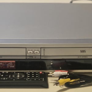 May include: A silver Sony DVD/VHS combo player with a black front panel and a remote control. The player has a DVD and VHS slot, and the remote control has buttons for both DVD and VHS functions.