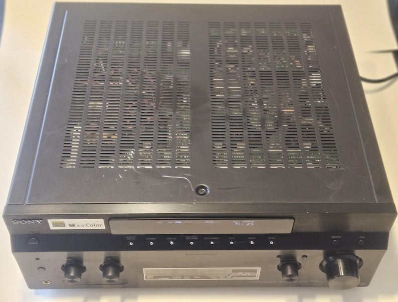 May include: Black Sony receiver with a silver faceplate and the text "Sony" and "x-Color" on the front. The receiver has a series of knobs and buttons on the front.