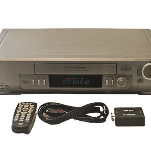 May include: A silver Sony Hi-Fi Stereo VHS player with a digital display showing 000:18. Included are a black remote control, a coiled black RCA cable, and a black Mini AV2HDMI converter box with the text MINI AV2HDMI 1080P printed on top.