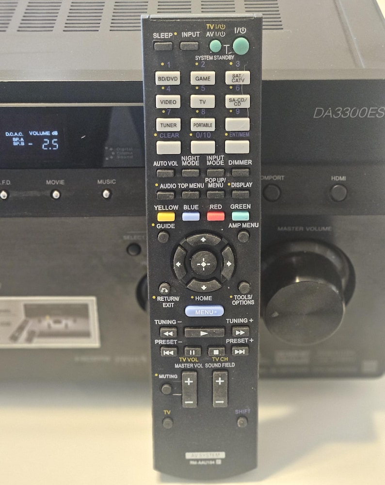 May include: A black remote control with a silver button for the "TV" function. The remote has a variety of buttons, including "Sleep", "Input", "Audio", "Menu", "Tools/Options", "Tuning", "Preset", "TV Vol", "TV Ch", "Master Vol", "Sound Field", "Muting", and "Shift". The remote also has a small screen that displays "DA3300ES".