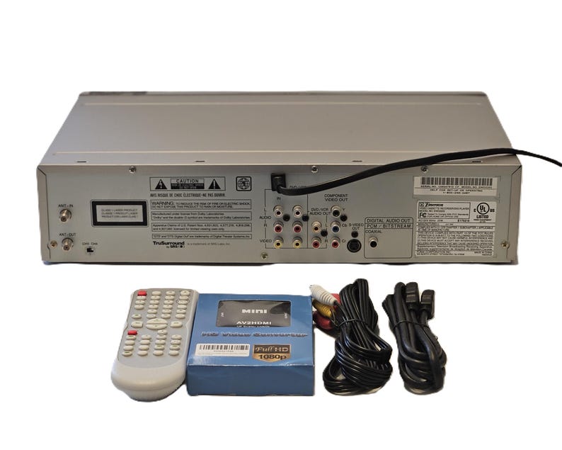 May include: Silver DVD player with a remote control, a blue box labelled "MINI AVERHDMI FULL HD 1080p", and various black and coloured cables. The DVD player has multiple input and output ports.