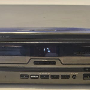 May include: A dark gray Technics compact disc changer with a digital display showing "17". The unit has multiple buttons and a CD tray. The text "6 CD CHANGER" is visible on the front panel.