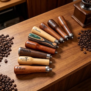 May include: A collection of eight wooden espresso machine handles with metal threaded ends. The handles feature various wood tones and finishes, with laser-engraved text including names like Ethan, William, Chloe, Theodore, and custom logos.