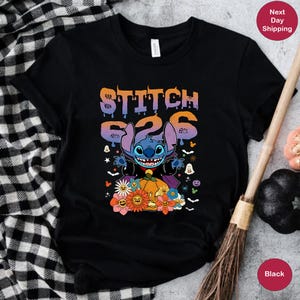 May include: Black t-shirt with a blue Stitch character dressed as a vampire holding a pumpkin. The text "Stitch 626" is above the character. The shirt has a Halloween theme with bats, ghosts, and flowers.