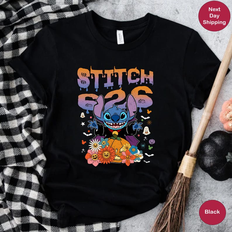 May include: Black t-shirt with a blue Stitch character dressed as a vampire holding a pumpkin. The text "Stitch 626" is above the character. The shirt has a Halloween theme with bats, ghosts, and flowers.