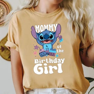 K&ouml;nnte beinhalten: Ein gelbes T-Shirt mit einer blauen Stitch-Figur aus Lilo & Stitch. Das Shirt tr&auml;gt den Schriftzug "Mommy of the Birthday Girl" und zeigt eine blaue Stitch-Figur, die einen Ballon h&auml;lt.