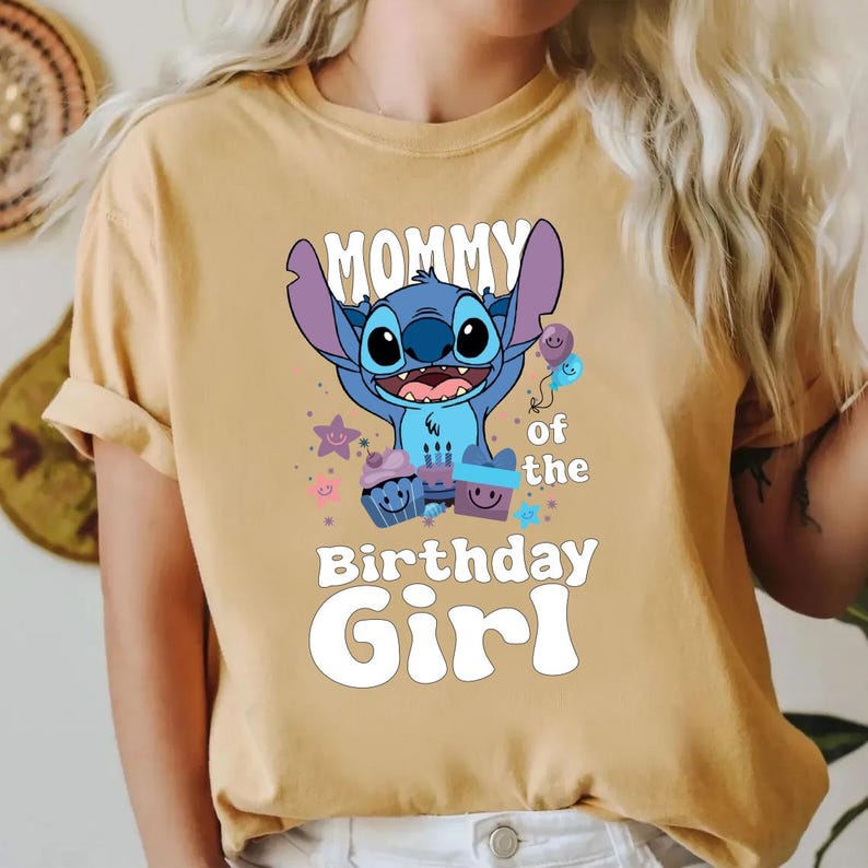 K&ouml;nnte beinhalten: Ein gelbes T-Shirt mit einer blauen Stitch-Figur aus Lilo & Stitch. Das Shirt tr&auml;gt den Schriftzug "Mommy of the Birthday Girl" und zeigt eine blaue Stitch-Figur, die einen Ballon h&auml;lt.