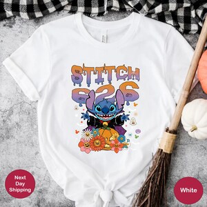 May include: White t-shirt with a blue Stitch character dressed as a vampire holding a pumpkin. The text "Stitch 626" is above the character. The shirt has a Halloween theme with ghosts, bats, and flowers.