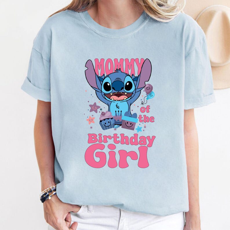 K&ouml;nnte beinhalten: Hellblaues T-Shirt mit einer blauen Stitch-Figur aus Lilo & Stitch. Das Shirt tr&auml;gt den Schriftzug "Mommy of the Birthday Girl" in rosa.
