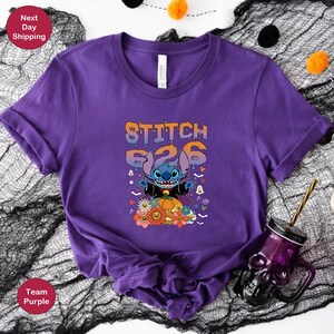 May include: Purple t-shirt with a blue Stitch character dressed as a vampire holding a pumpkin. The text "Stitch 626" is above the character in orange and yellow.