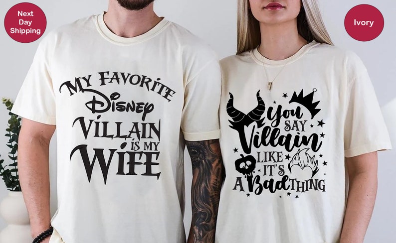 May include: Two ivory t-shirts with black text and graphics. The first shirt says "My Favorite Disney Villain is My Wife". The second shirt says "You Say Villain Like It's A Bad Thing" with a graphic of Maleficent's horns and a crown.
