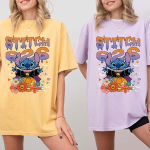 May include: Two women wearing oversized t-shirts with a Stitch Halloween design. The shirts are yellow and purple with the text "Stitch 626" and a cartoon image of Stitch dressed as a vampire.