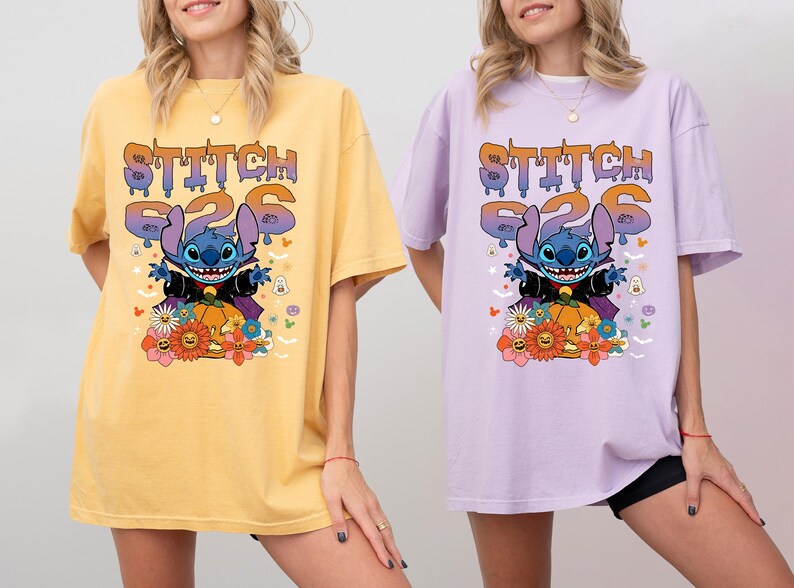 May include: Two women wearing oversized t-shirts with a Stitch Halloween design. The shirts are yellow and purple with the text "Stitch 626" and a cartoon image of Stitch dressed as a vampire.