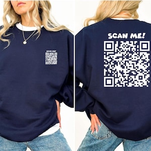 May include: A navy blue sweatshirt with a white QR code and the text "SCAN ME!" printed on the back. The sweatshirt has a crew neck and long sleeves.