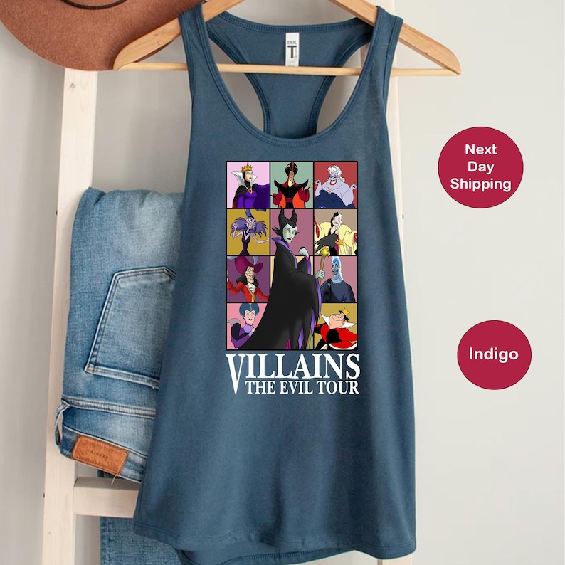 Op de afbeelding: Een blauwe tanktop met een raster van tekenfilm-schurken. De afbeelding bevat personages als Maleficent en de boze koningin, met de tekst "VILLAINS THE EVIL TOUR" onder de afbeeldingen. De tanktop hangt aan een houten hanger.