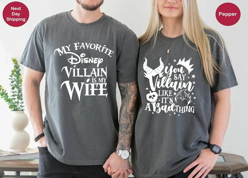May include: Two gray t-shirts with white text. The first shirt says "My Favorite Disney Villain is My Wife". The second shirt says "You Say Villain Like It's A Bad Thing".