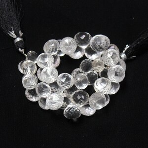 Puede incluir: Una hebra de cuentas de cristal facetadas transparentes con borlas negras en cada extremo.